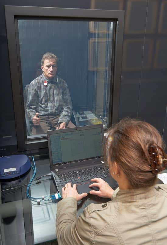 Client In Hearing Booth Having Hearing Test